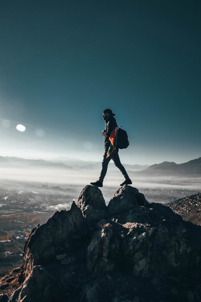 A lone hiker conquering rocky peaks in Nawur, Afghanistan under a clear sky.